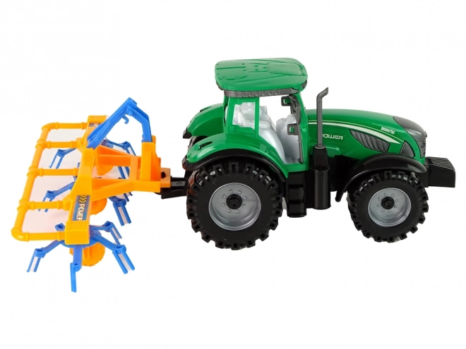 Grüner Traktor mit orange-blauem Schwader mit Reibungsantrieb