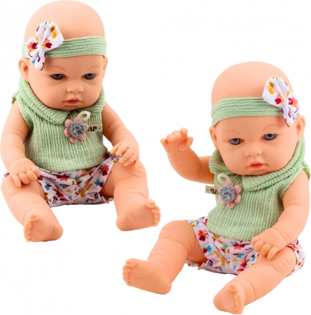 Baby-Puppe im grünen Outfit mit Blumenmuster und Haarband mit Schleife